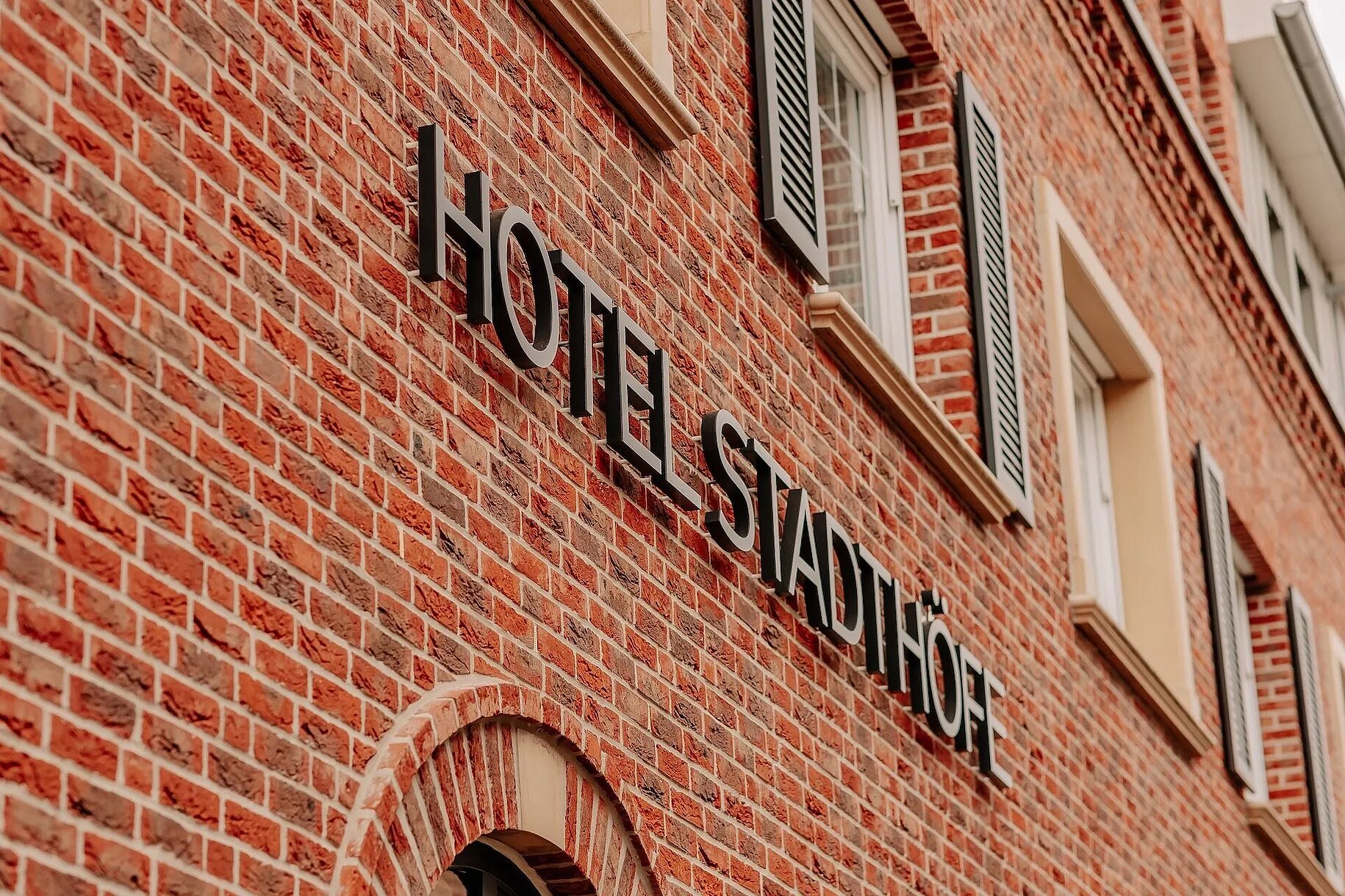 Fassadendetail mit Logo-Schriftzug des Hotel Stadthöfe Rhede auf rotem Backstein