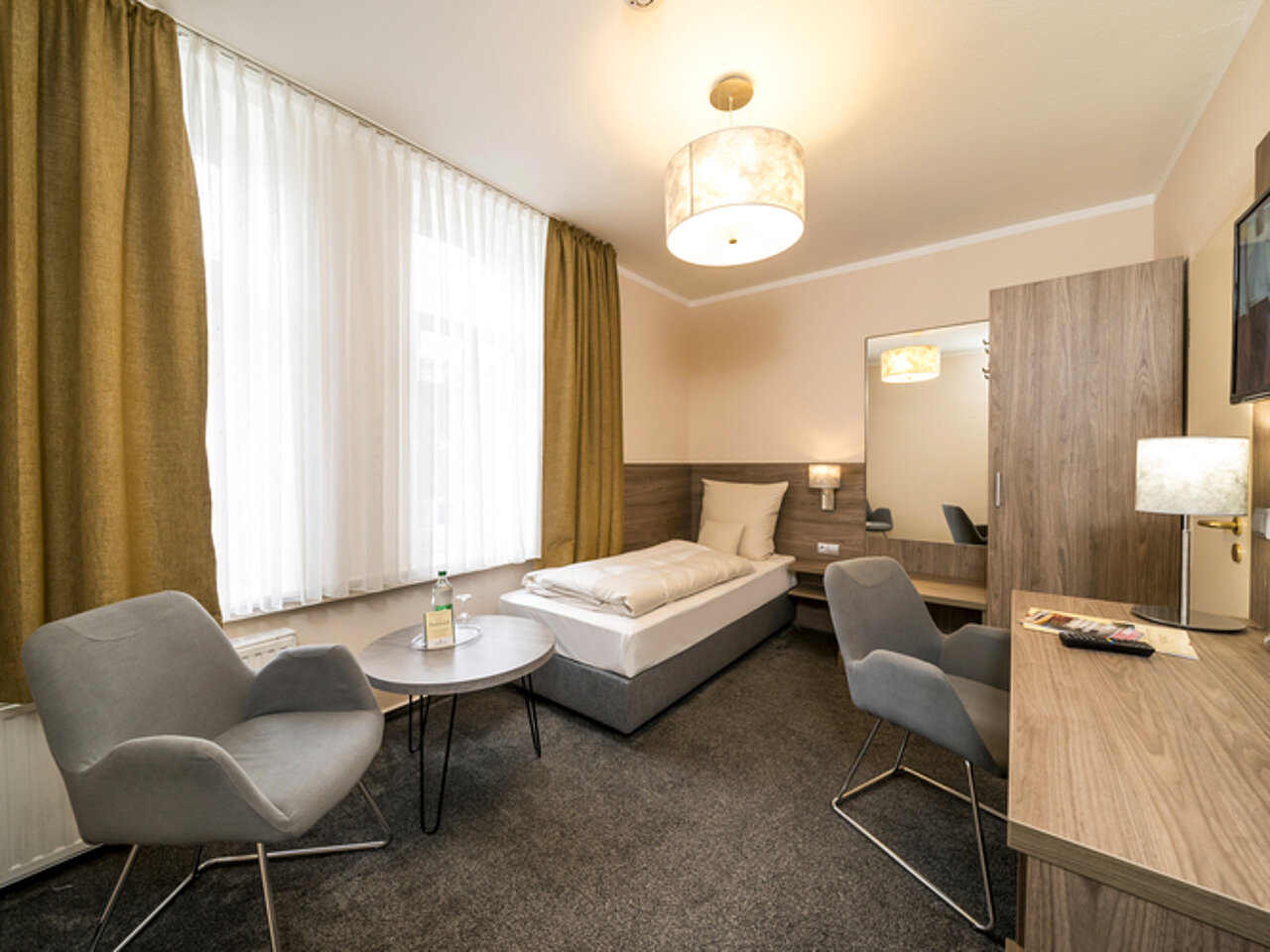 Einzelzimmer mit Schreibtisch und Sessel im Parkhotel Lingen