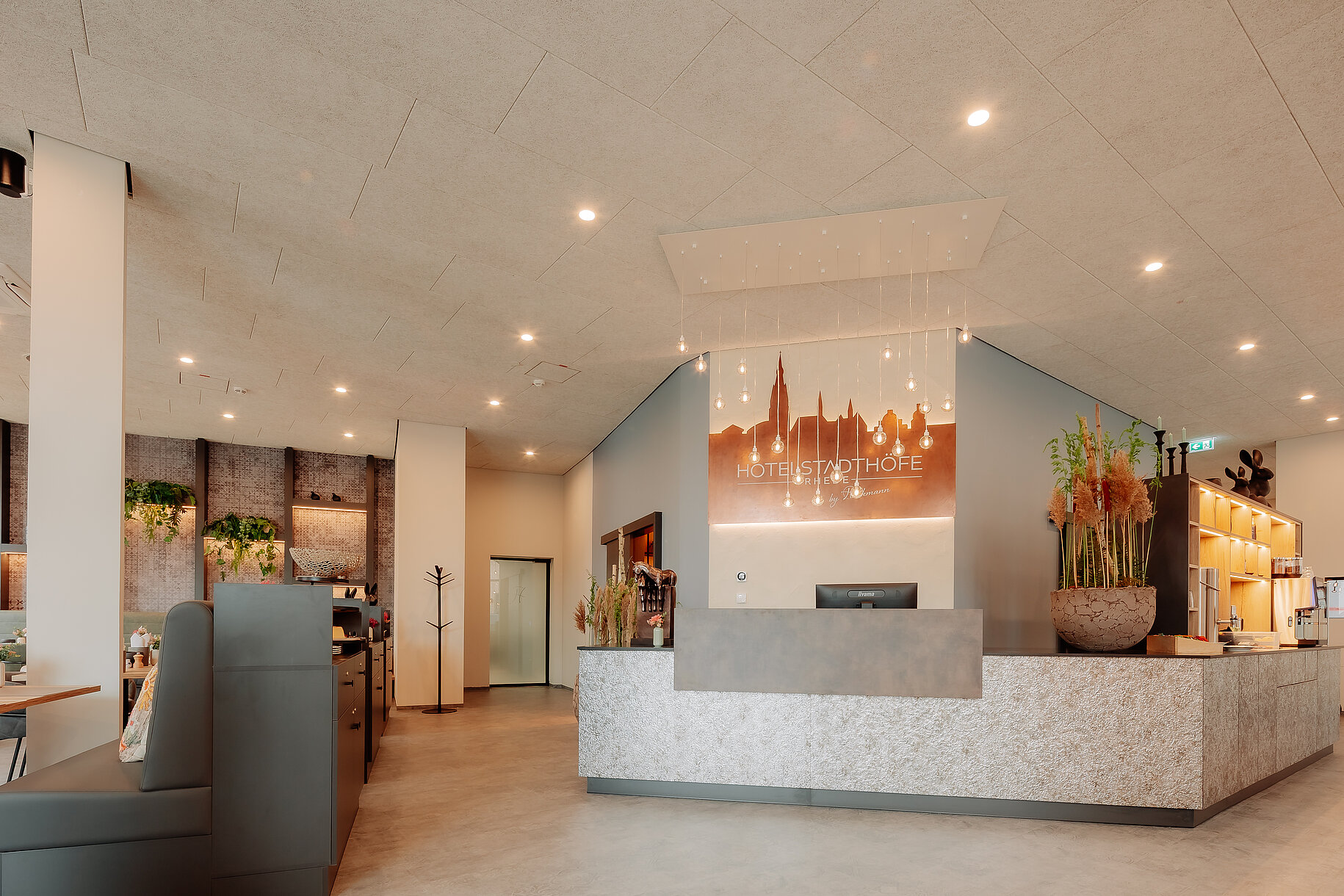 Moderne Rezeption im Hotel Stadthöfe Rhede mit beleuchtetem Stadt-Silhouettenlogo