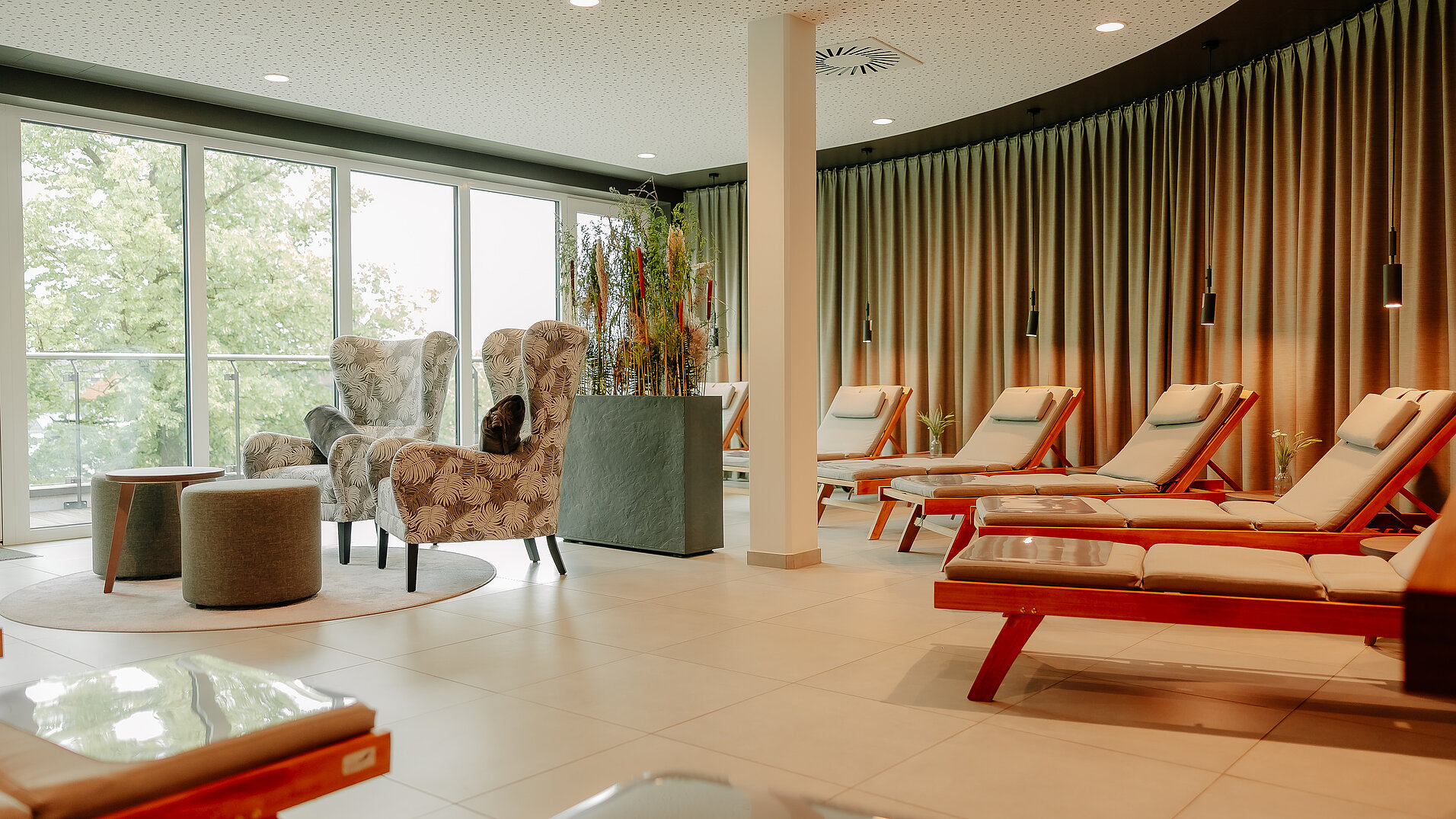 Bequeme Liegen im stilvollen Ruheraum mit großen Fenstern und Waldblick