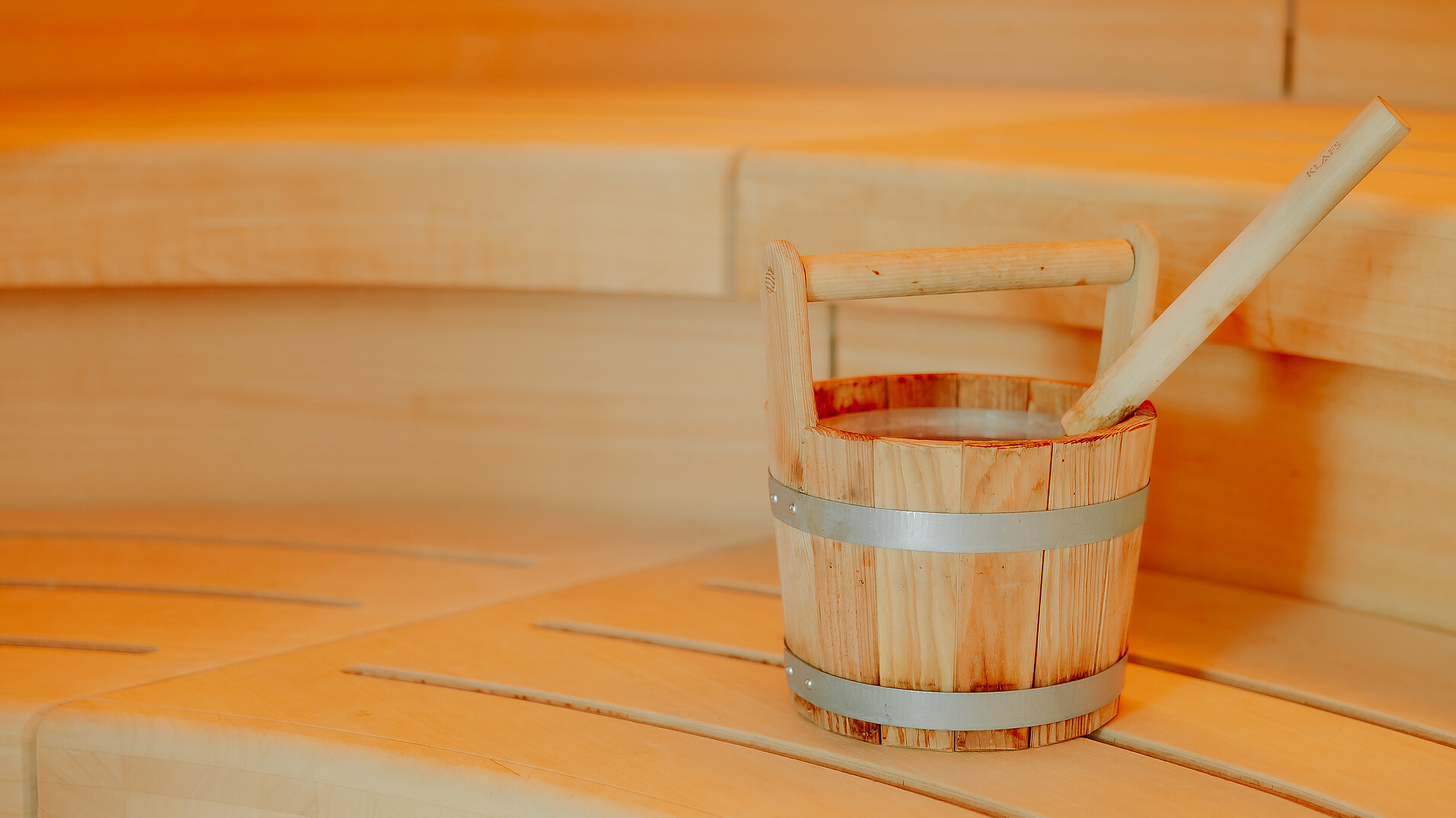 Klassischer Saunaeimer aus Holz auf Bank in der finnischen Sauna