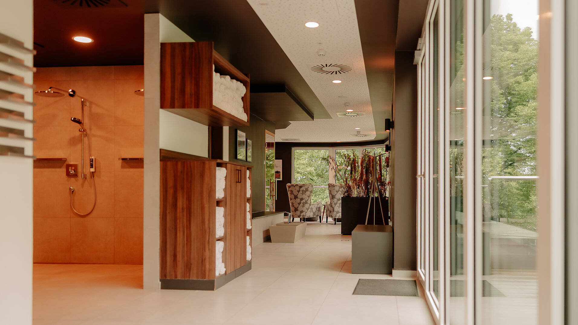 Lichtdurchfluteter Gang im Wellnessbereich mit Duschen und Handtüchern
