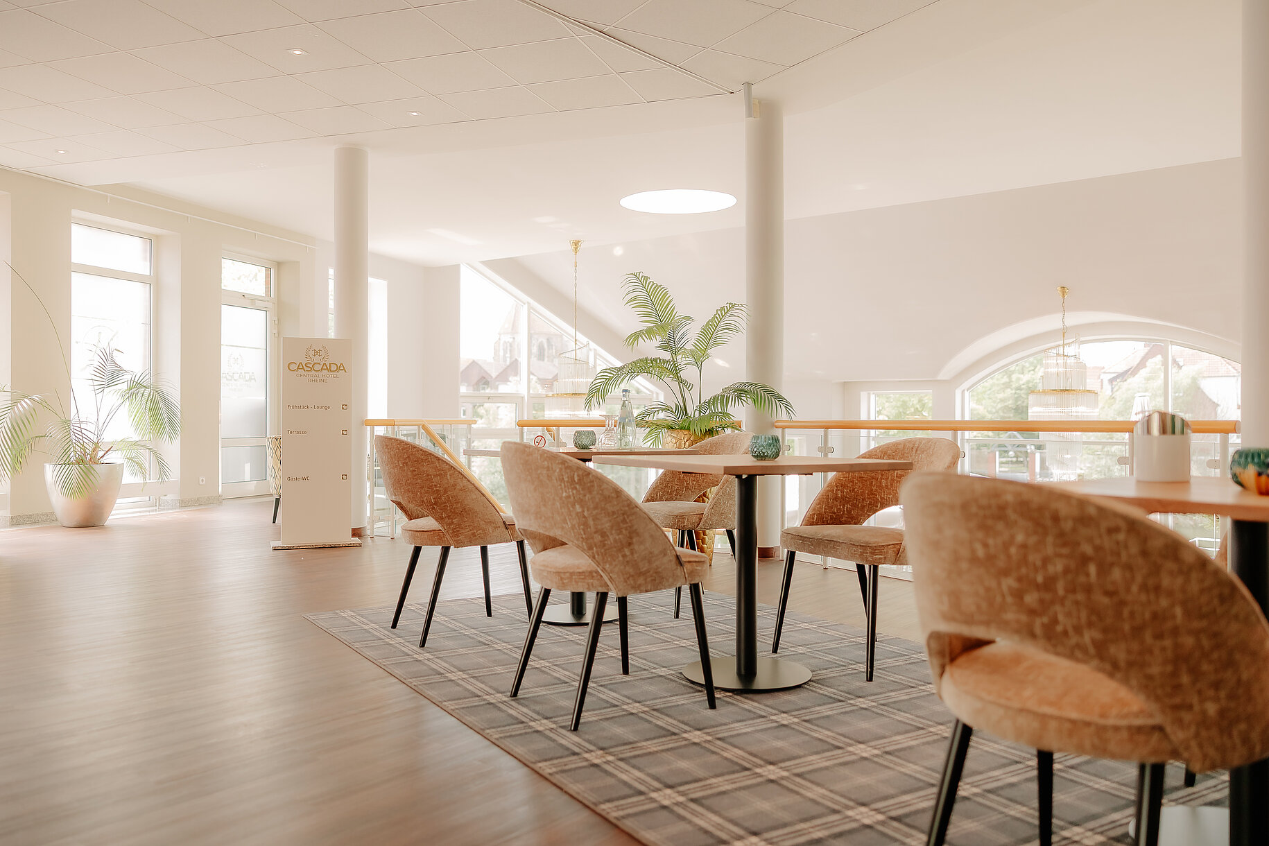 Heller Loungebereich mit Sitzgruppen in der Lobby des CASCADA Hotels Rheine