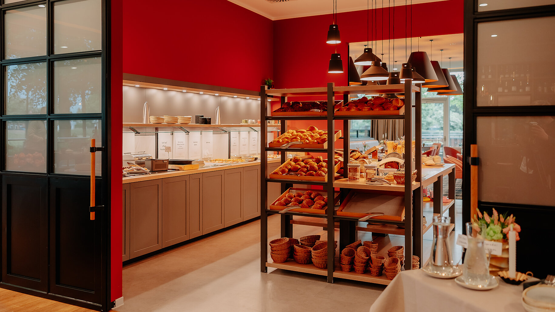 Reichhaltige Brötchenauswahl und Frühstücksbuffet in einem stilvoll eingerichteten Raum mit roten Wänden