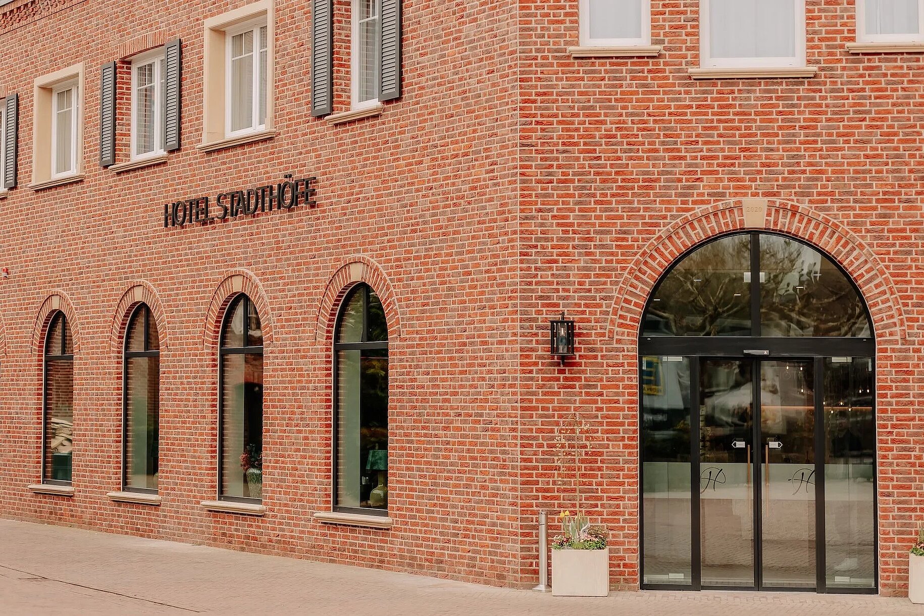 Außenansicht des Hotel Stadthöfe Rhede mit roter Klinkerfassade und Rundbogenfenstern