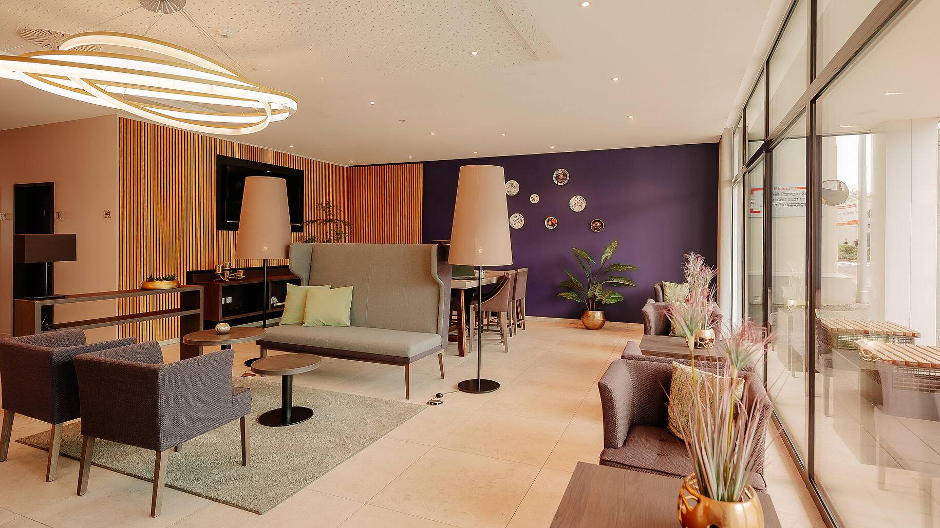Stilvoll eingerichteter Loungebereich mit violetter Akzentwand und modernen Sitzmöbeln im LOOKEN INN Lingen