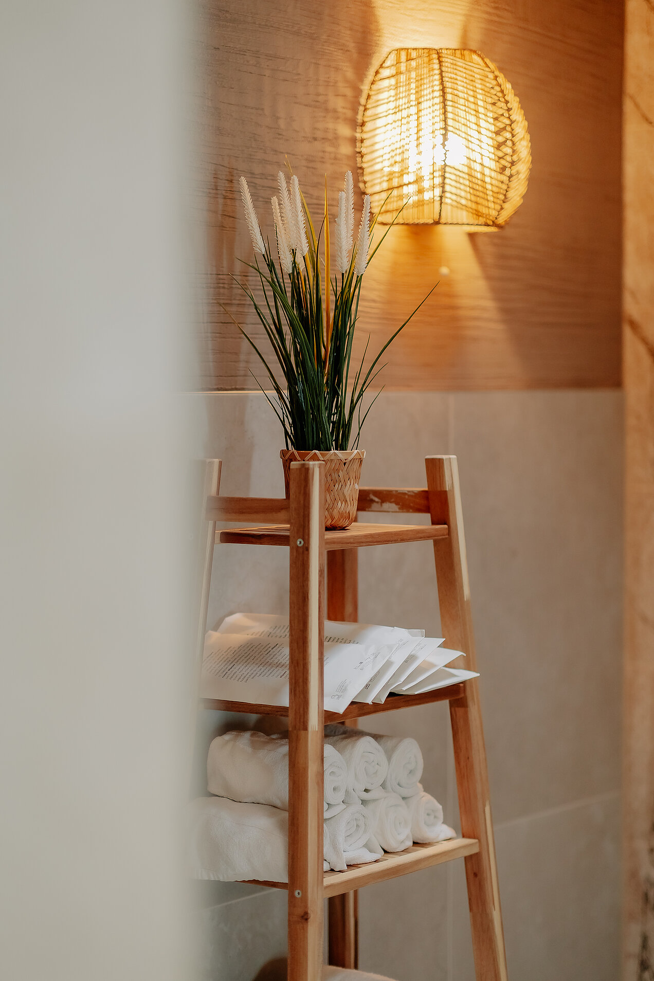Regal mit Handtüchern und Pflanze unter Wandleuchte im Ruhebereich
