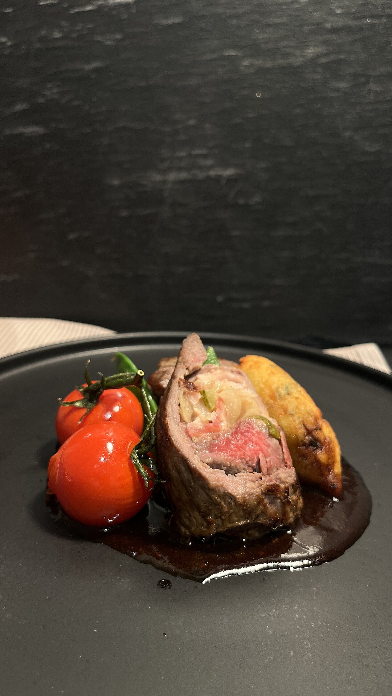 Klassisch gefüllte Rumpsteak-Roulade mit Portwein-Schalotten-Jus, Röstzwiebeln, Zuckerschoten, Kirschtomaten und Dauphine-Kartoffeln.