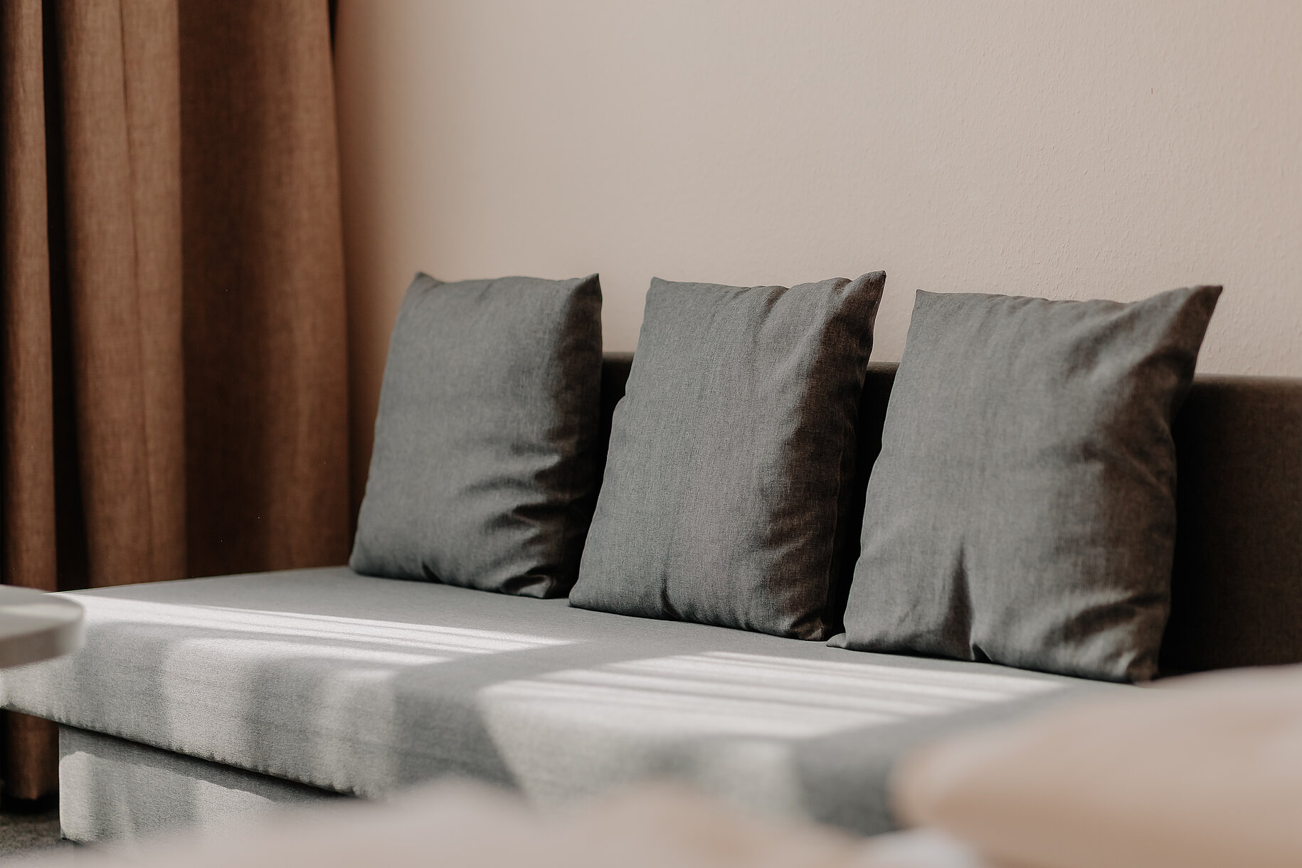 Graues Sofa mit Kissen im Hotelzimmer des Parkhotels Lingen