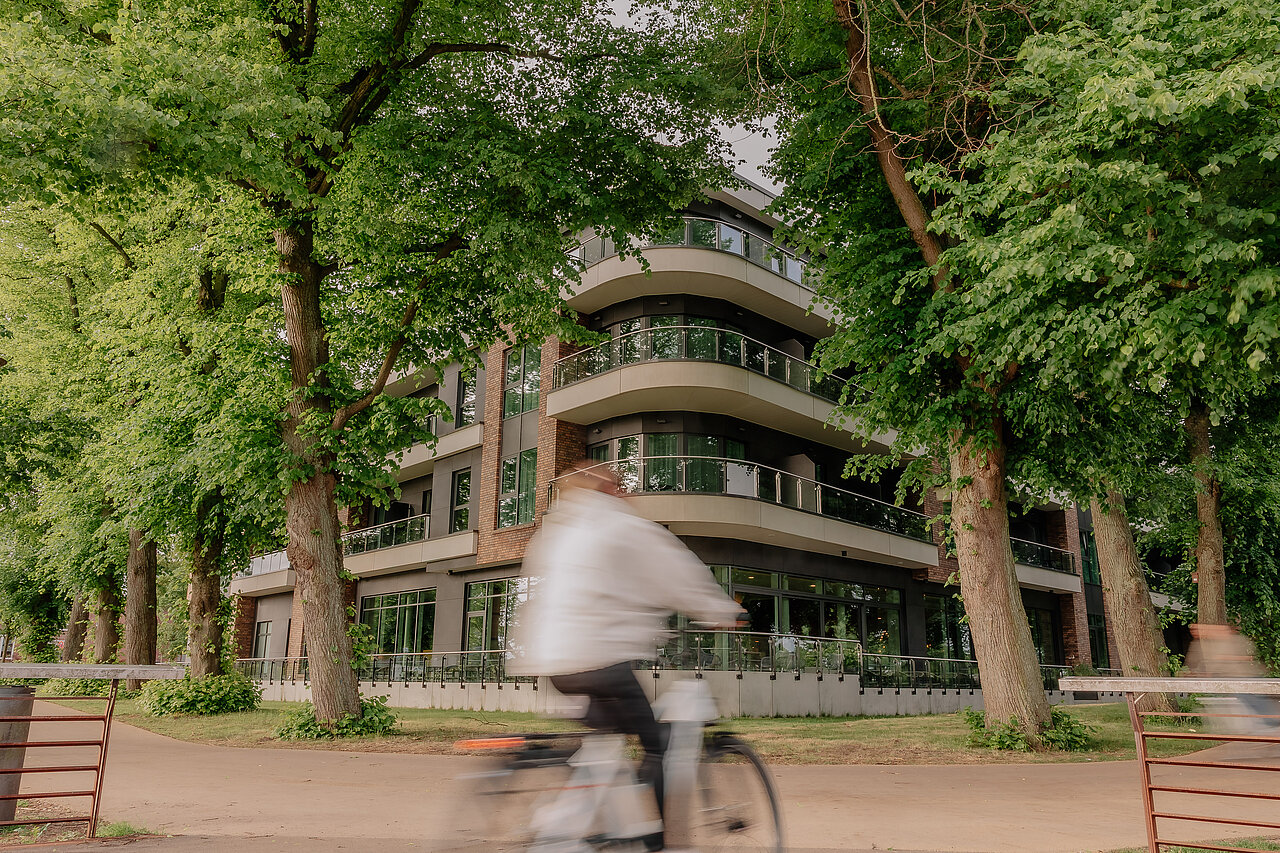 Radfahrerin vor dem grün umrahmten VIA PLAZA Hotel in Meppen