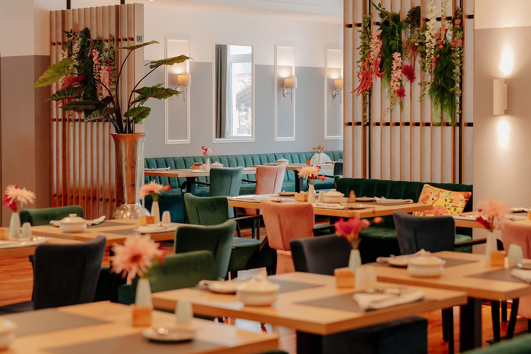 Heller und stilvoll dekorierter Frühstücksraum mit bunten Polsterstühlen und floralen Akzenten im Stadthotel Borken