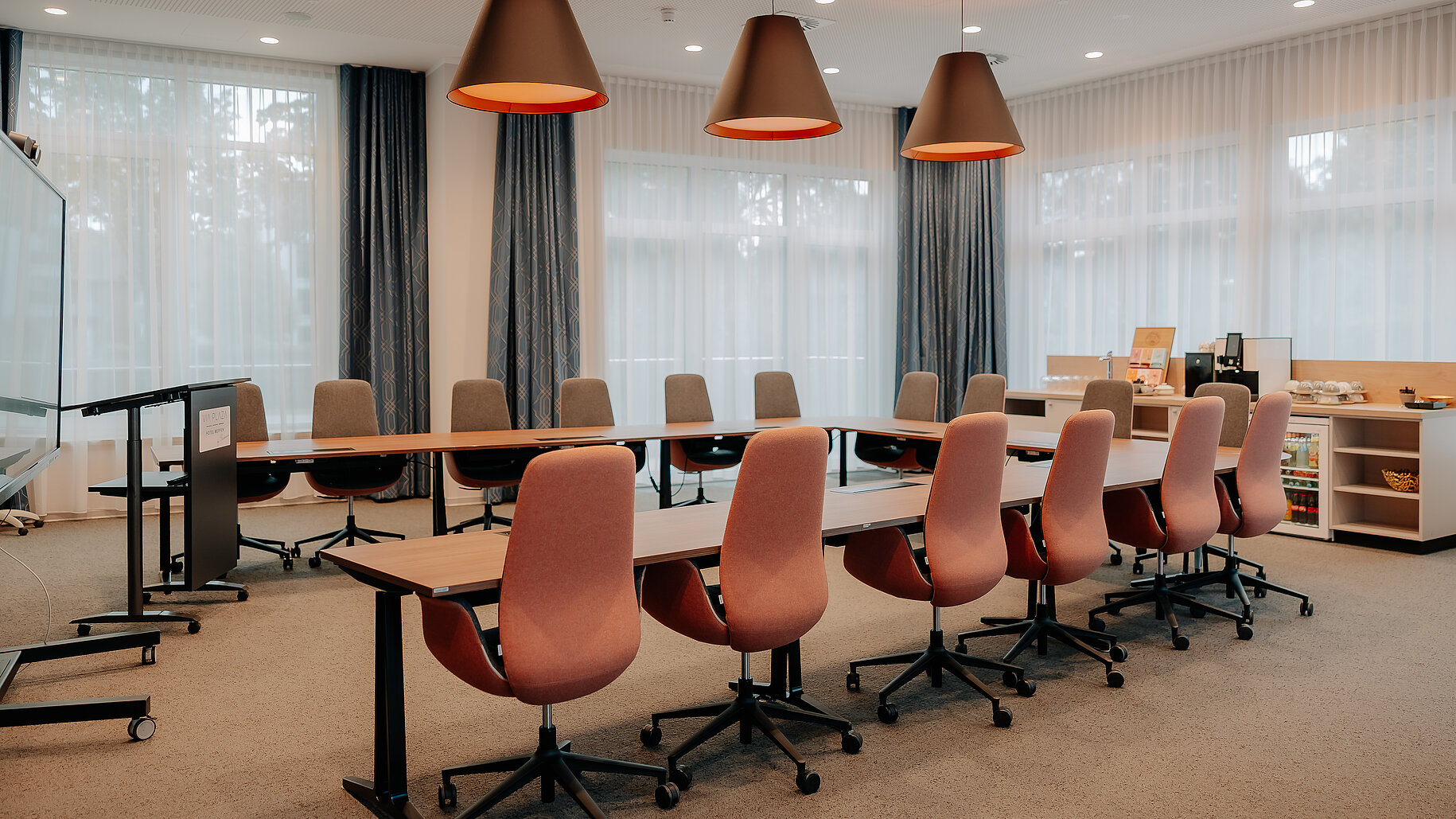 Moderner Tagungsraum mit U-förmiger Bestuhlung, komfortablen Stühlen und großer Fensterfront im VIA PLAZA Meppen.