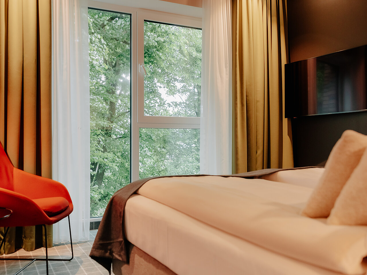 Doppelzimmer mit stilvoller Einrichtung und Fensterblick auf grüne Baumkronen