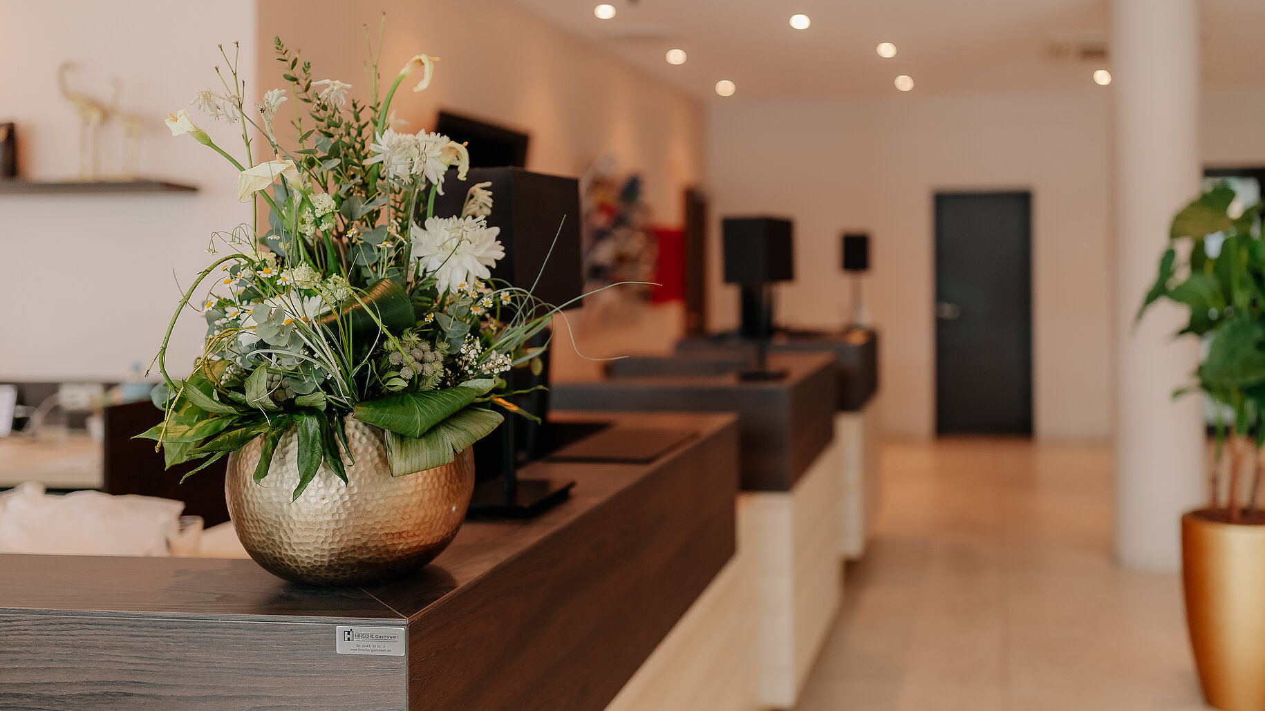 Empfangsbereich im LOOKEN INN Lingen mit stilvollem Blumenschmuck auf der Theke