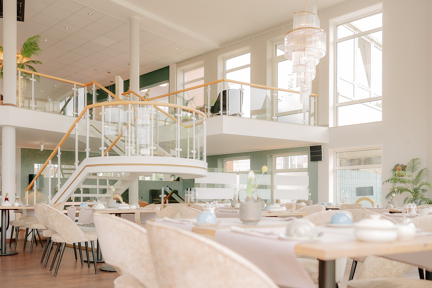 Heller, moderner Restaurantbereich mit eleganter Treppe und großen Fenstern im CASCADA Hotel Rheine