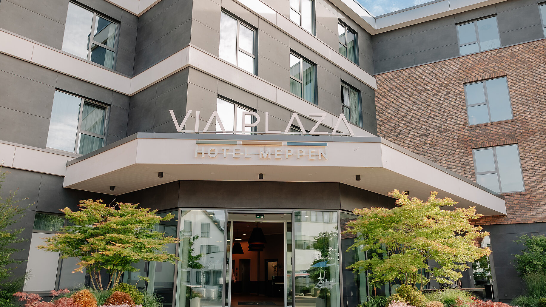 Haupteingang des VIA PLAZA Meppen mit Glasfront und begrüntem Eingangsbereich