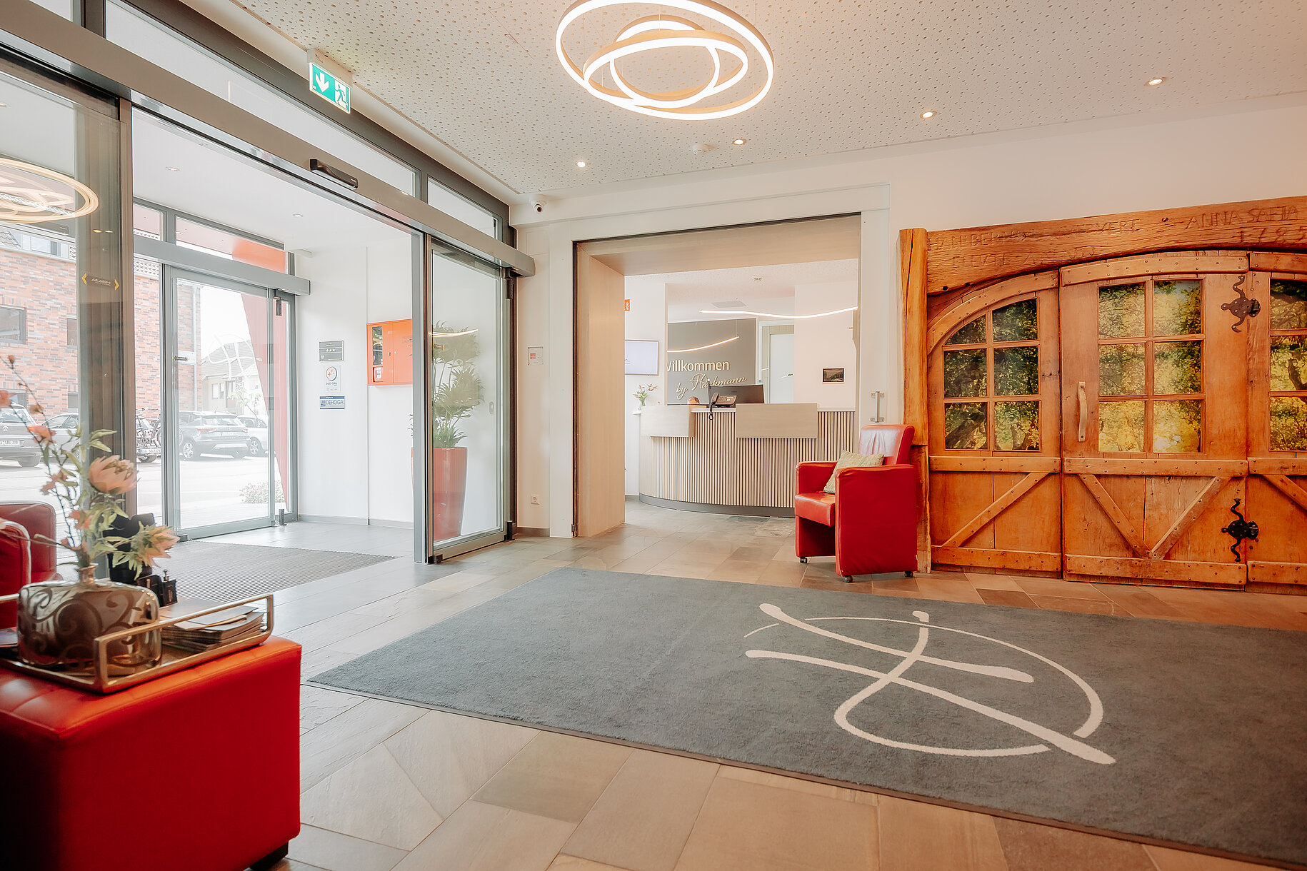 Moderner Eingangsbereich mit Blick auf die Rezeption und rustikale Holztür im Parkhotel Papenburg