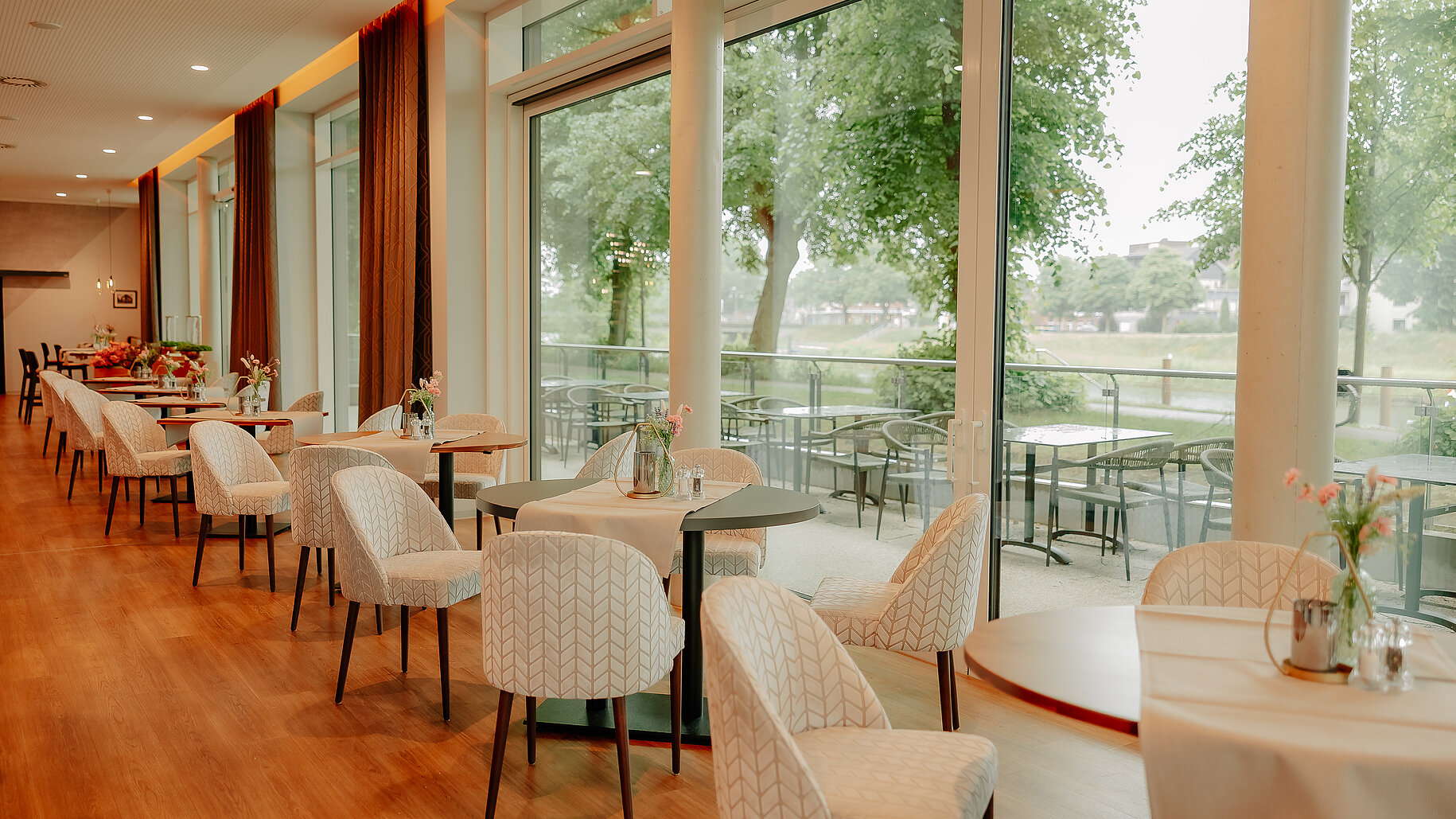 Gedeckte Tische im Restaurant des VIA PLAZA mit Blick auf die Außenterrasse