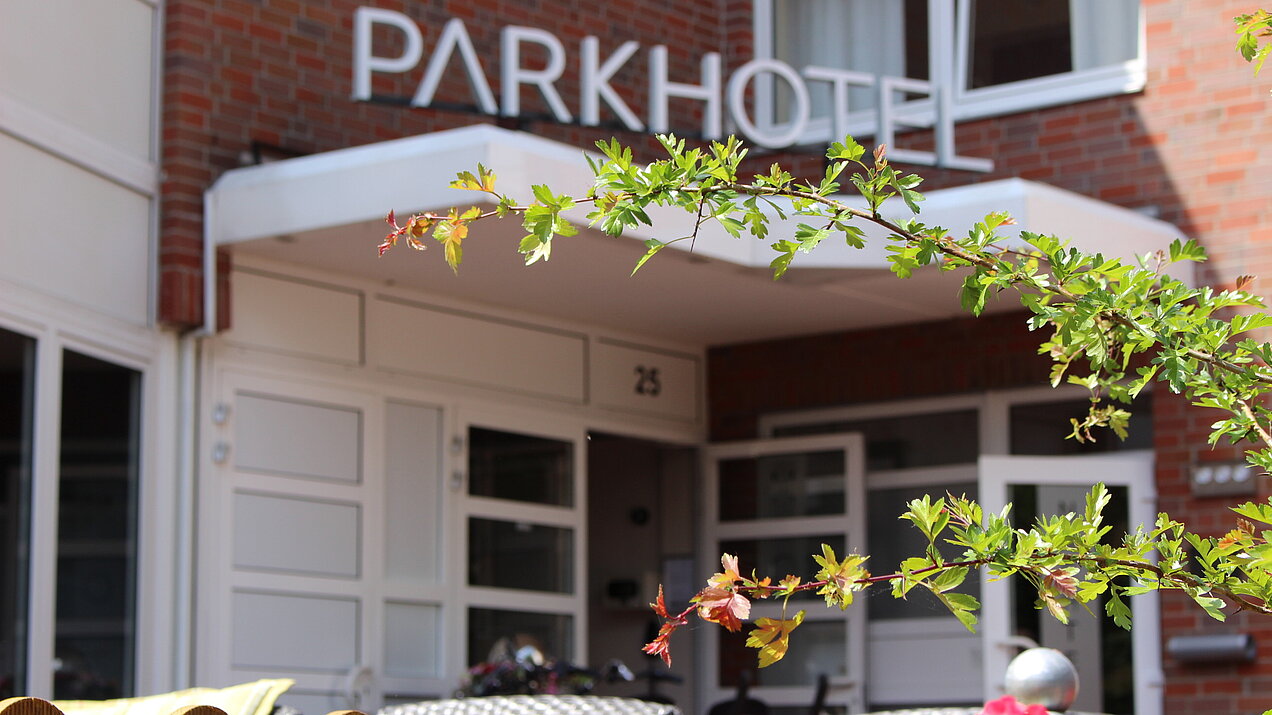 Eingangsbereich des Parkhotels Papenburg mit blühenden pinken Blumen im Vordergrund