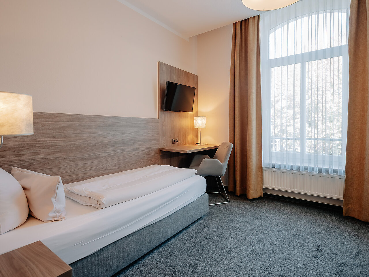 Einzelzimmer mit Schreibtisch und Sessel im Parkhotel Lingen