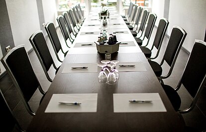 Tagungsraum im Parkhotel Papenburg mit eingedecktem Konferenztisch Eingedeckter Tagungstisch mit Stühlen und Konferenzausstattung in modernem Ambiente.