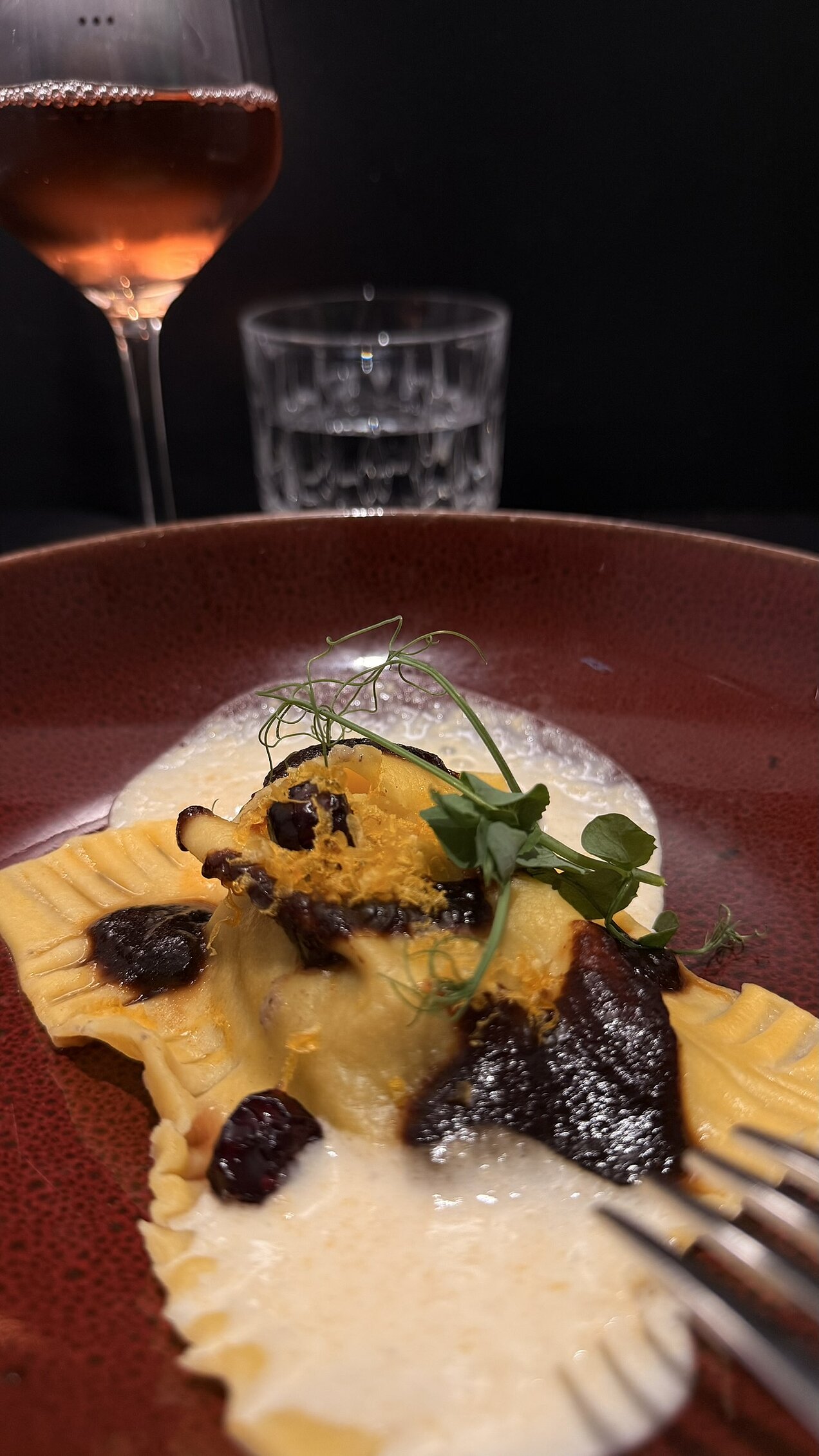 Hausgemachte Ravioli mit Pilzleber, serviert mit stark reduzierter Gemüse-Jus, Cranberrys, Parmesanschaum und gebeiztem Eigelb.