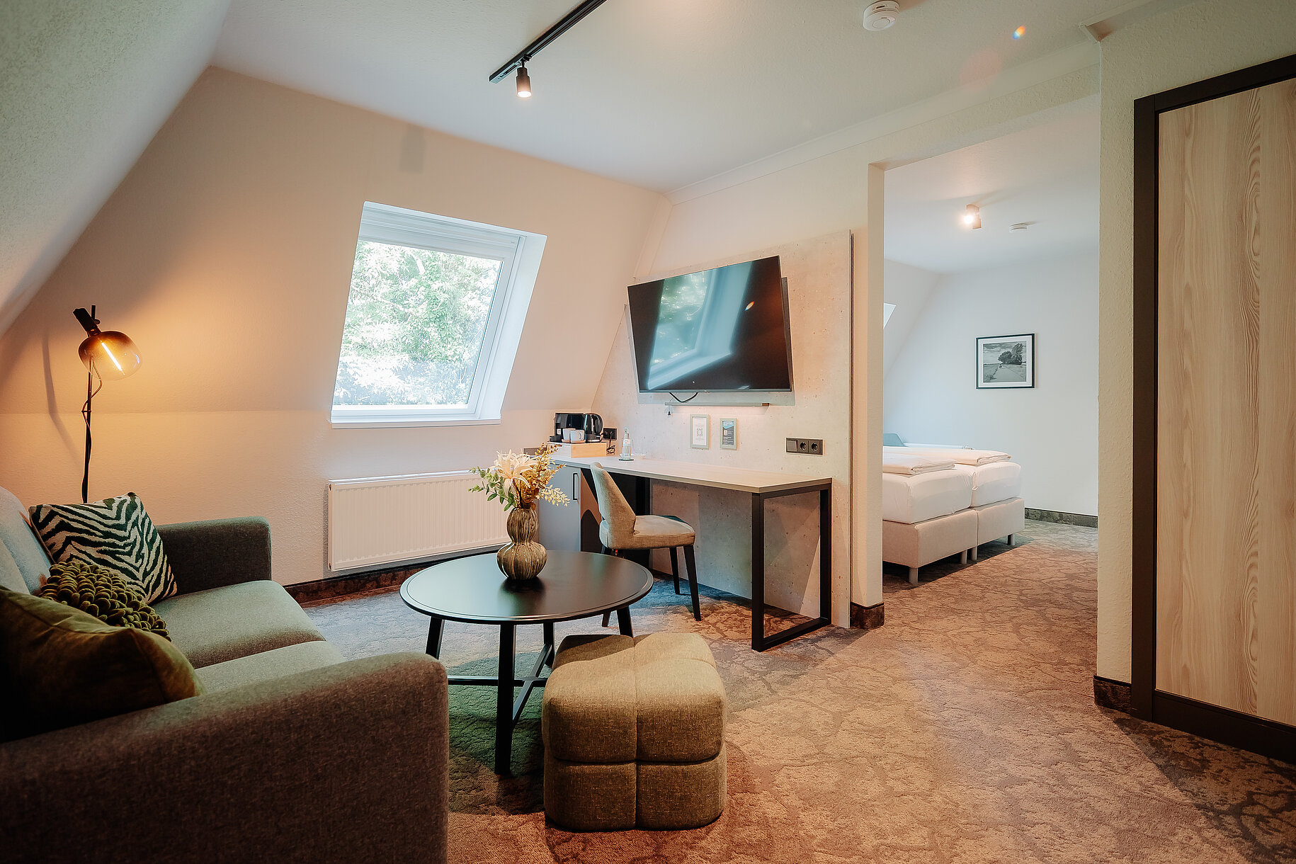 Modernes Komfort Zimmer im Parkhotel Papenburg mit Doppelbett, Sitzbereich und offenem Badezimmer.